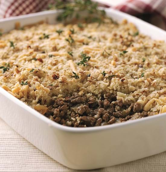 A close up of the savoury mince crumble in a serving dish on a table. A serving has already been taken.